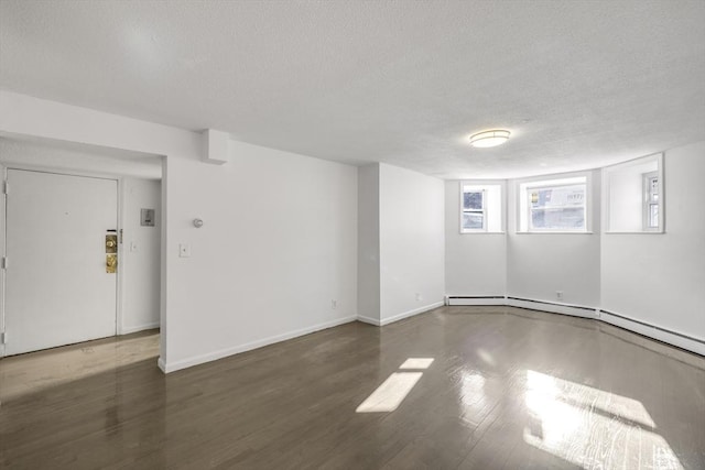 unfurnished room featuring a textured ceiling, dark hardwood / wood-style flooring, and baseboard heating