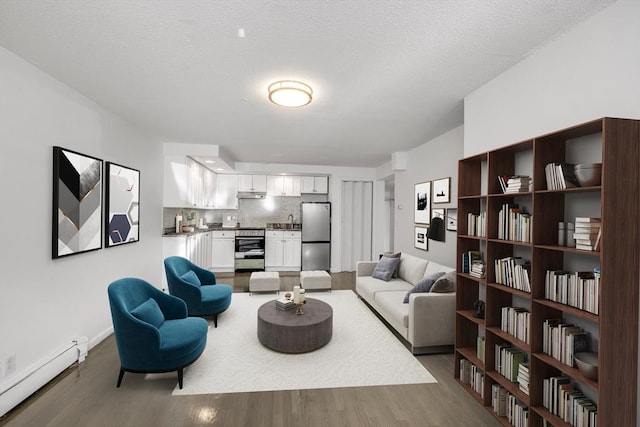 living room with hardwood / wood-style flooring, baseboard heating, and a textured ceiling