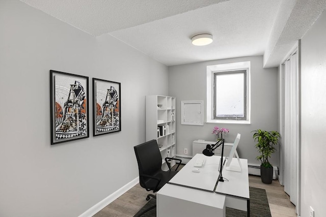 office area featuring a textured ceiling, light wood-type flooring, and baseboard heating