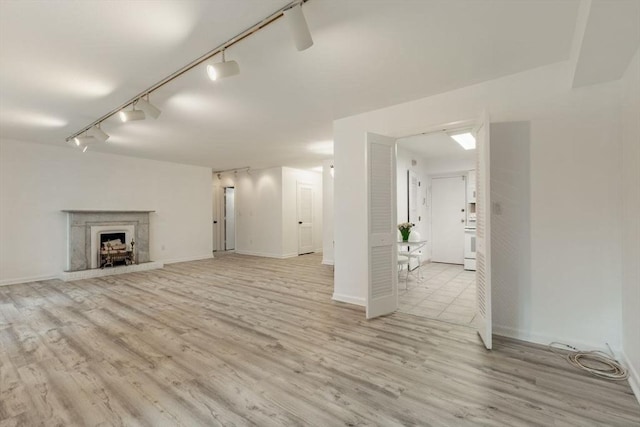 unfurnished living room featuring baseboards, a fireplace with raised hearth, and wood finished floors