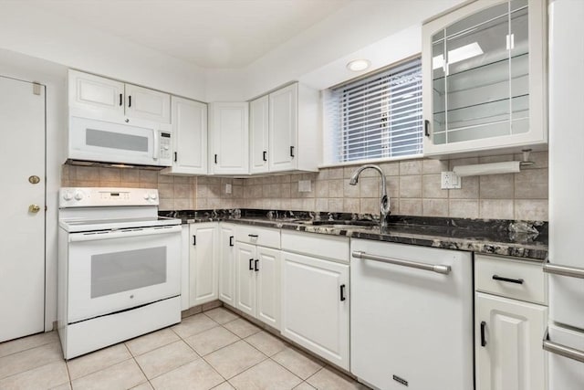 kitchen with white appliances, light tile patterned flooring, a sink, and white cabinets