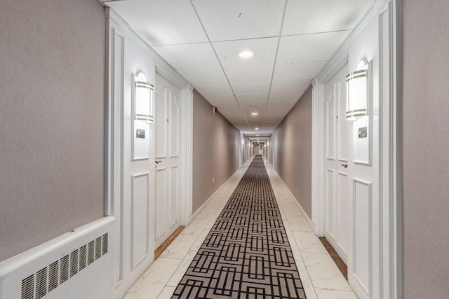 corridor with recessed lighting, marble finish floor, a drop ceiling, and baseboards