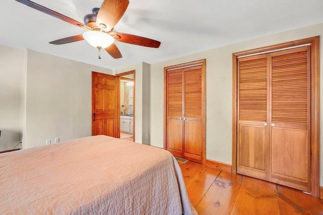 bedroom featuring two closets, ceiling fan, and light hardwood / wood-style floors