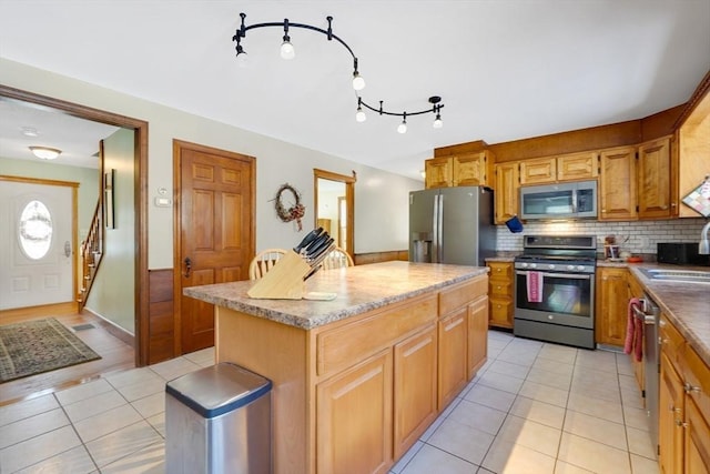 kitchen featuring a kitchen island, stainless steel appliances, light tile patterned floors, and sink