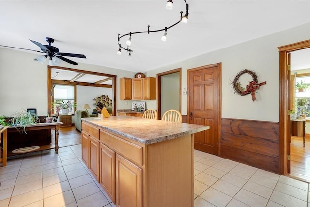 kitchen featuring ceiling fan, a center island, light tile patterned flooring, and plenty of natural light