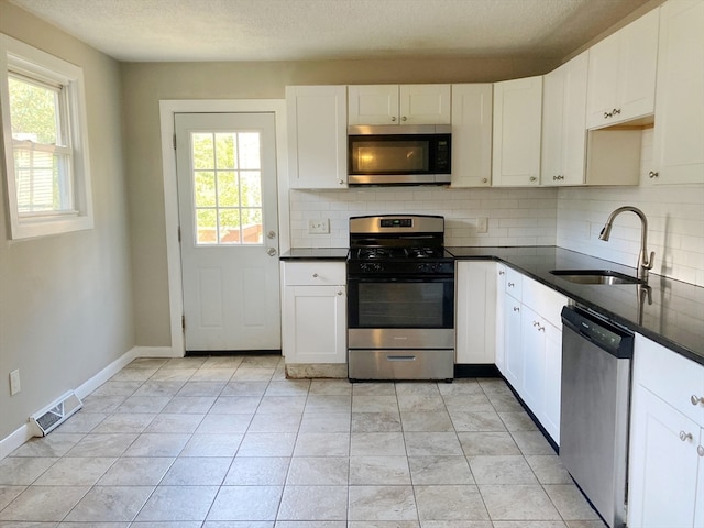 kitchen with sink, stainless steel appliances, white cabinets, backsplash, and light tile patterned flooring