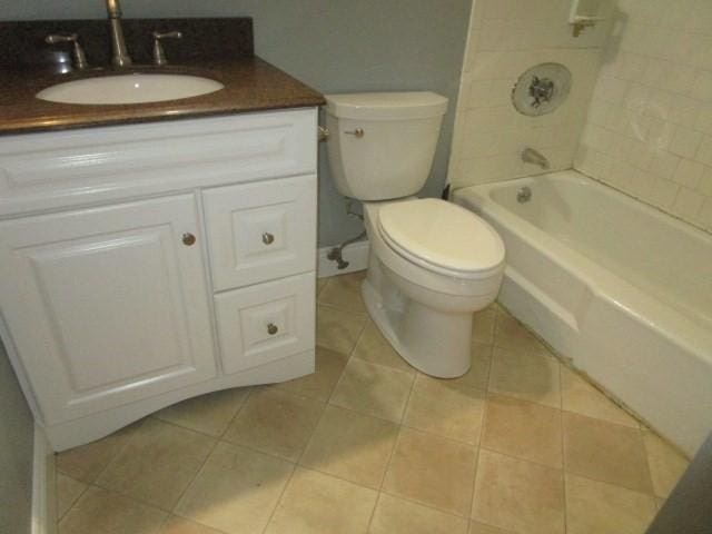 full bathroom with tile patterned floors, tiled shower / bath, vanity, and toilet