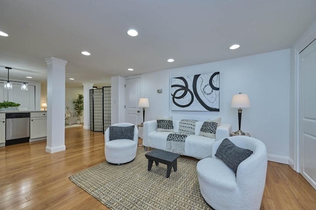 living room featuring recessed lighting, baseboards, light wood-type flooring, and ornate columns