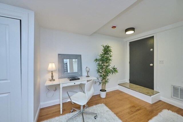 office with baseboards, visible vents, and wood finished floors