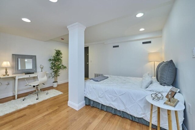 bedroom with ornate columns, visible vents, and wood finished floors
