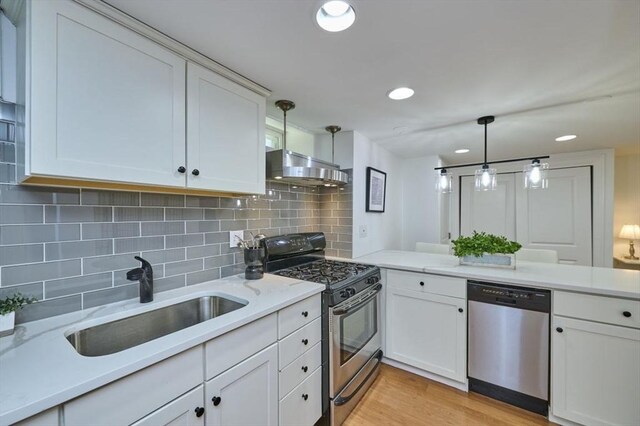 kitchen featuring a sink, stainless steel appliances, white cabinetry, backsplash, and under cabinet range hood