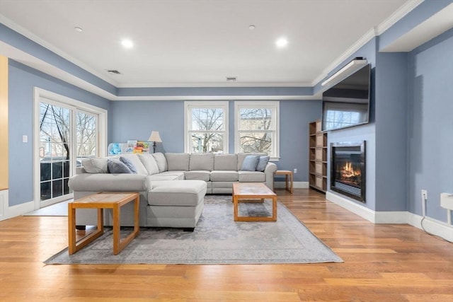 living room with a healthy amount of sunlight, light hardwood / wood-style flooring, and crown molding