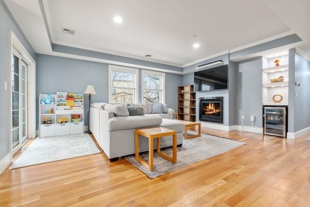 living room with beverage cooler, light hardwood / wood-style flooring, and ornamental molding