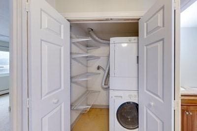 clothes washing area featuring stacked washer / drying machine