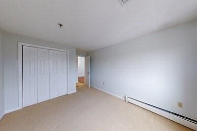 unfurnished bedroom with baseboard heating and light colored carpet