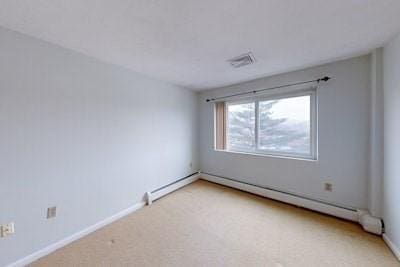 carpeted spare room featuring baseboard heating