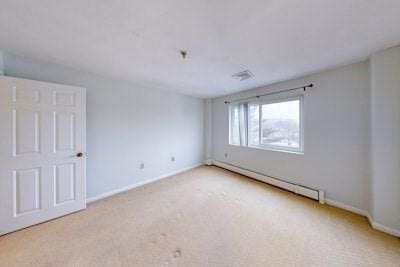 empty room with light carpet and a baseboard radiator