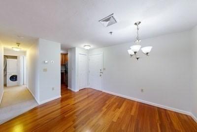 empty room featuring light hardwood / wood-style floors and a notable chandelier