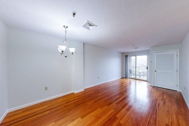 empty room featuring hardwood / wood-style flooring and a chandelier