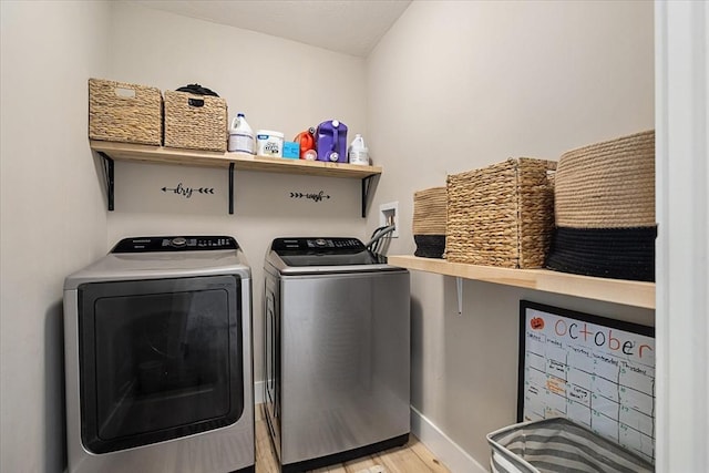 clothes washing area with baseboards, washer and clothes dryer, laundry area, and wood finished floors