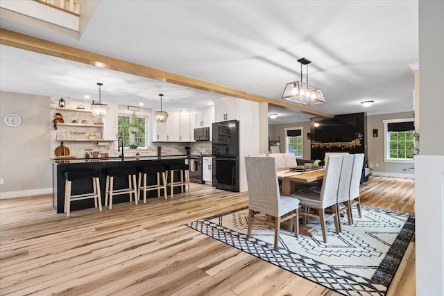 dining space featuring light wood-type flooring, crown molding, baseboards, and a notable chandelier