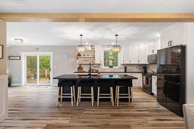 kitchen featuring dark countertops, black appliances, a breakfast bar area, and white cabinetry