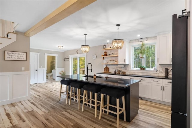 kitchen featuring an inviting chandelier, white cabinetry, dark countertops, a kitchen bar, and a sink