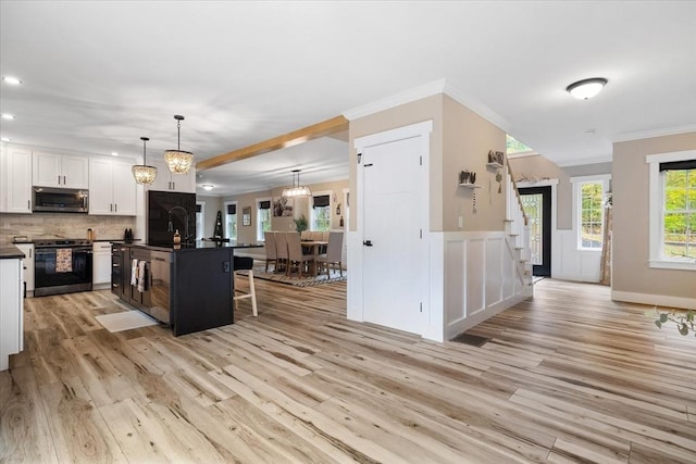 kitchen featuring white cabinets, dark countertops, black / electric stove, stainless steel microwave, and light wood-style flooring