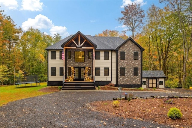 view of front facade with french doors, a trampoline, and a front yard