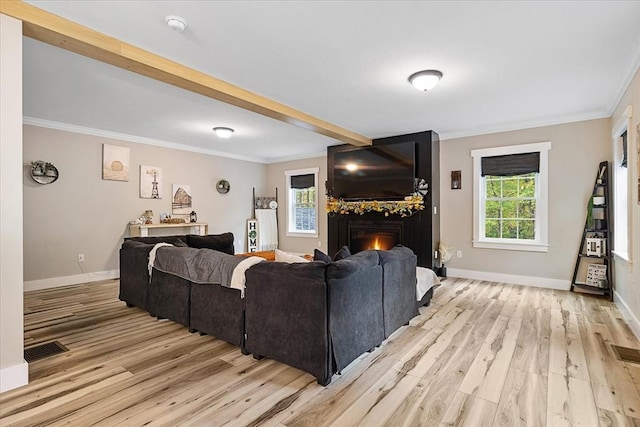 living room featuring visible vents, baseboards, a warm lit fireplace, light wood-style floors, and crown molding