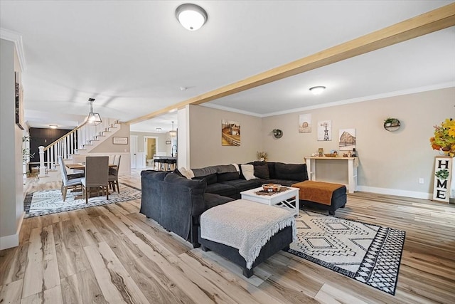 living room featuring crown molding, light wood finished floors, baseboards, and stairs
