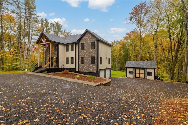 view of front of property with a garage, a porch, and a storage unit