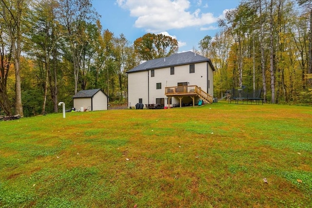 rear view of property with a deck, a trampoline, a lawn, an outdoor structure, and stairway