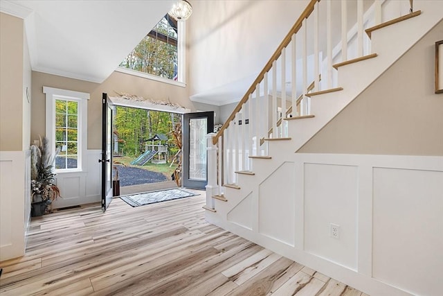 entrance foyer featuring a decorative wall, stairway, a wainscoted wall, and wood finished floors