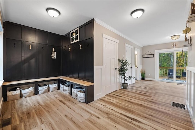 mudroom featuring crown molding, visible vents, light wood-type flooring, and a decorative wall