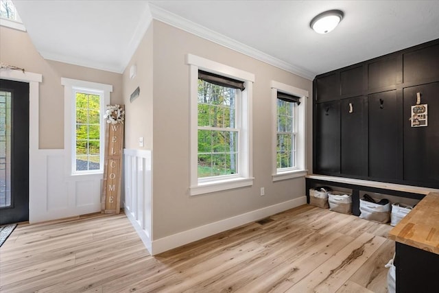 mudroom with baseboards, crown molding, a wainscoted wall, a decorative wall, and light wood finished floors