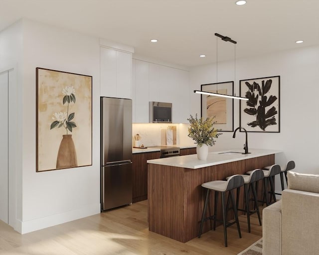 bar area featuring stainless steel appliances, light wood finished floors, a sink, recessed lighting, and pendant lighting