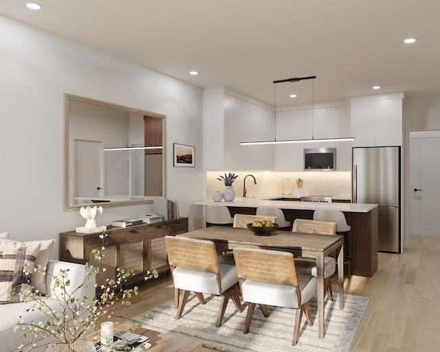 kitchen featuring stainless steel fridge, modern cabinets, light wood-type flooring, light countertops, and white cabinetry