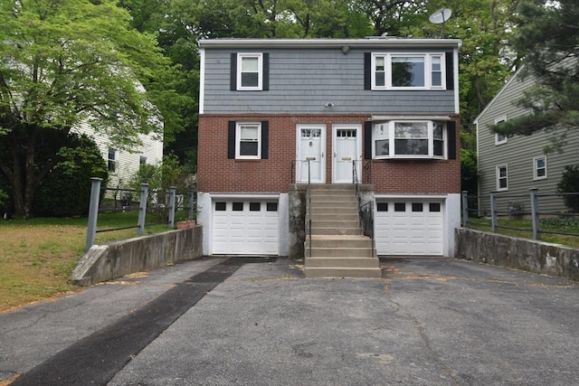 view of front of home with asphalt driveway, a garage, fence, and brick siding
