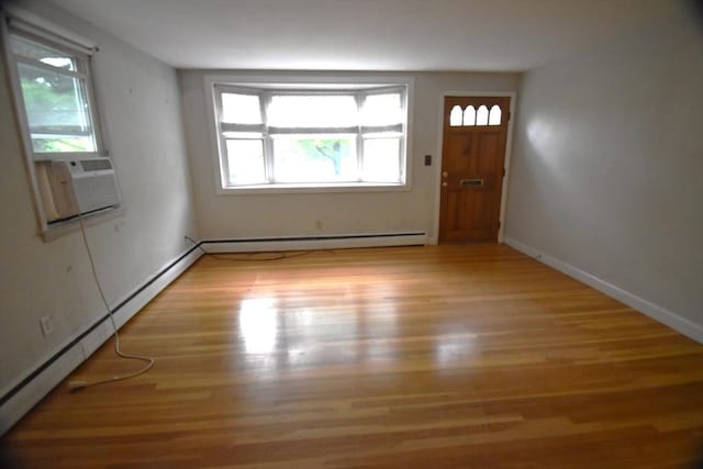 foyer entrance with a baseboard heating unit, light wood-type flooring, cooling unit, and baseboards