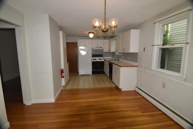 kitchen with electric range oven, baseboard heating, freestanding refrigerator, under cabinet range hood, and a sink