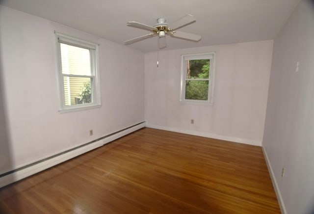 spare room featuring baseboard heating, wood finished floors, ceiling fan, and baseboards