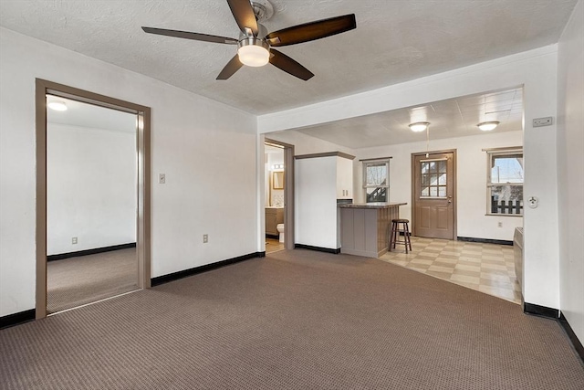 unfurnished living room with ceiling fan, light colored carpet, and a textured ceiling