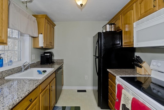 kitchen featuring light stone counters, white appliances, and sink