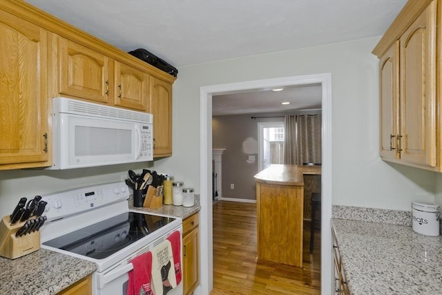 kitchen with light stone counters, white appliances, light brown cabinets, and light wood-type flooring