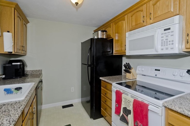 kitchen with light stone counters, white appliances, and sink