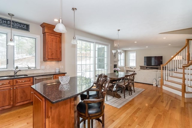 kitchen featuring dishwasher, light hardwood / wood-style floors, a kitchen island, sink, and tasteful backsplash