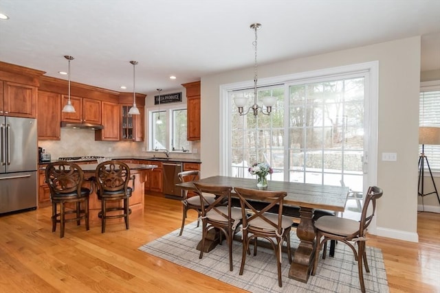 dining space featuring sink, light hardwood / wood-style flooring, and a chandelier