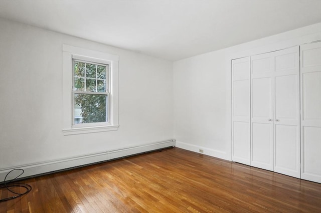 14 Lyman Ter, Waltham, MA 02452 - unfurnished bedroom with a baseboard heating unit, wood finished floors, and a closet