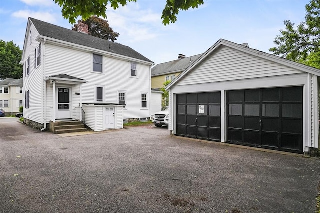 14 Lyman Ter, Waltham, MA 02452 - view of front of property featuring a garage, a chimney, and an outdoor structure